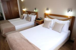 布拉加索菲亚多纳酒店的配有白色枕头的酒店客房内的两张床