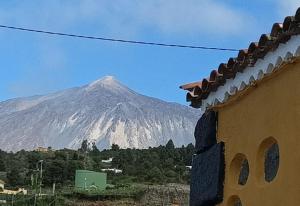 伊科德洛斯维诺斯Tradicional Casa Canaria con piscina y vistas al Teide的一座有积雪覆盖的山,与一座建筑相隔不远