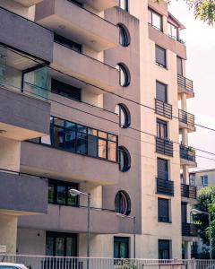 普洛耶什蒂MOZART RESIDENCE PLOIEȘTI Family and Business Apartment的一座高大的建筑,拥有圆形的窗户和街边的灯光