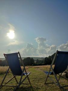 波思利文Porthleven Glamping的两把椅子坐在天空中阳光的田野里