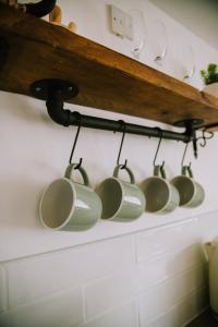 滨海凯斯特Pebbles Cottage的挂在架子上的一排咖啡杯