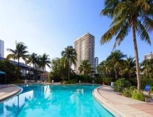 迈阿密海滩Sunny Isles Miami HOLIDAY apartment的一座棕榈树游泳池和一座高高的建筑