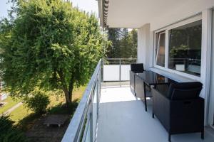 韦齐孔Moderne & helle Wohnung mit Netflix & Bergsicht的阳台配有桌椅和一棵树。