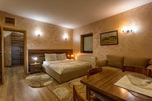 兹拉蒂博尔Apartment Vila Simovic的一间卧室配有一张床、一张沙发和一张桌子