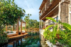 图卢姆Hotel Shibari - Restaurant & Cenote Club的楼前有池塘的房子