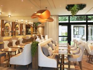 圣日耳曼昂莱Mercure Paris Ouest Saint Germain的餐厅设有白色的椅子和桌子以及窗户。