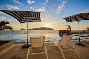 马萨特兰Courtyard by Marriott Mazatlan Beach Resort的俯瞰大海的庭院配有2把椅子和遮阳伞