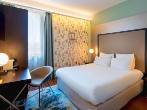 安锡Le Splendid Hotel Lac D'Annecy - Handwritten Collection的酒店客房设有一张白色大床和一张书桌