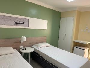 马塞约Hotel Porto Grande的客房设有两张床、一张小桌子和一盏灯。