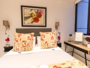 开普敦Flamingo Sea Point Sea View Luxury Best Position 1 Bedroom Apartment Queen Size Bed & Inverter For TV的卧室配有一张床,墙上挂有绘画作品