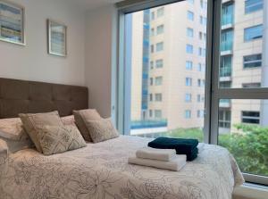 直布罗陀Luxury 1 Bed Apt - City Suites Ocean Spa Plaza的窗户前的一张带毛巾的床