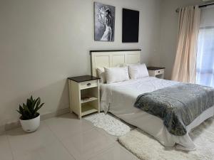 卢萨卡Kaya Apartments的一间卧室配有一张床和盆栽植物