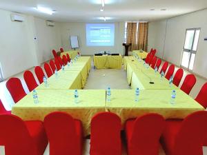 朱巴Juba Landmark Hotel的一间会议室,配有桌子和红色椅子以及屏幕