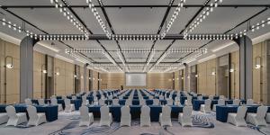 杭州杭州滨奥皇冠假日酒店的大房间设有蓝色的桌子和白色的椅子