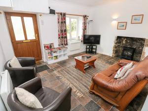 彭布罗克No 2 New Cottages的客厅配有真皮沙发和椅子