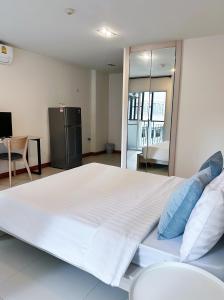 曼谷The Lodge @ Min Residence的一张大白色的床,里面配有蓝色枕头