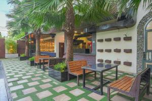 阿姆利则Hotel Escala By Levelup的庭院设有长椅和桌子,种有棕榈树
