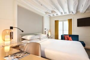 巴黎里什庞斯歌剧院酒店的卧室配有一张白色的大床和一张桌子