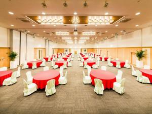 岛原市Hotel Seaside Shimabara的一个带红色桌子和白色椅子的大型宴会厅