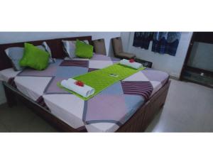 KushinagarHotel Mamta Palace, Kushinagar的一间卧室配有两张带绿色枕头的床