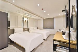 蔚山Hotel Rubato Ulsan Jung-gu Haksung的酒店客房设有两张床和电视。