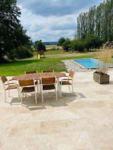 Bligny-lès-BeauneLogement B / Clos des Saunières的一张木桌和椅子,旁边是游泳池
