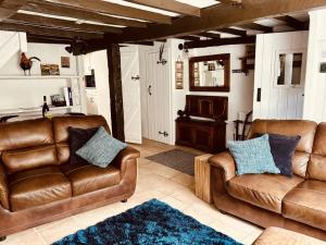 阿斯克里格The Roost - Askrigg 18th Century Cottage的客厅配有两张真皮沙发和地毯。