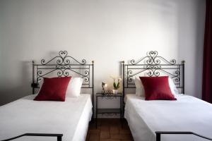 古比奥圣马可酒店的卧室内的两张床和红色枕头