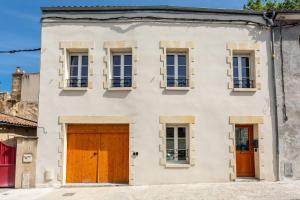 洛尔蒙Joli appartement avec jardin / Vieux-Lormont的白色的房子,设有棕色的门和窗户
