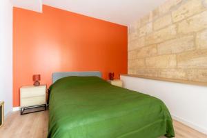 洛尔蒙Joli appartement avec jardin / Vieux-Lormont的一间卧室设有绿色的床和橙色的墙壁
