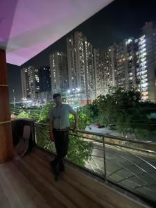 加济阿巴德Luxurious 3 BHK Flat in Ghaziabad的一个人晚上站在城市的阳台上
