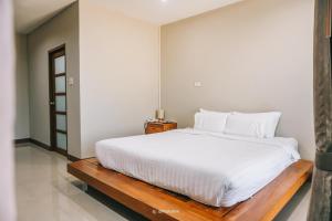 素可泰Na Sukhothai Hotel的一间卧室配有一张白色大床和木凳