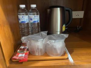 素可泰Na Sukhothai Hotel的咖啡壶旁的切纸板上放两瓶水