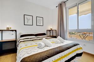 多列毛利诺斯Vistamarina A409 By IVI Real Estate的卧室配有带枕头的床铺和窗户。