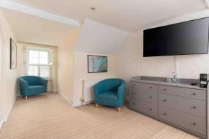 马拉扎恩Room 6, Hotel style Double bedroom in Marazion的客房设有2把蓝色椅子和带电视的梳妆台。