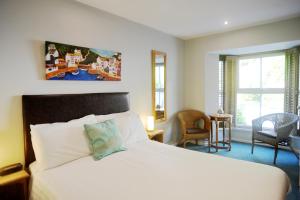 波尔佩罗Penryn House Hotel的卧室配有白色的床、椅子和窗户。