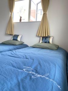 札幌Arts Candy Sapporo-Villa Nakajima的一间卧室设有两张带蓝色床单和窗户的床。