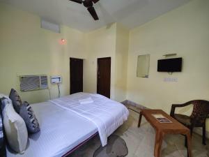 普里Hotel Surya Greens的一间卧室配有一张床、一张桌子和一台电视。