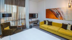 利雅德Centro Olaya by Rotana的酒店客房设有黄色的沙发和电视。
