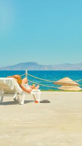 达特恰Feri Surf Club Hotel Datça的躺在沙滩上椅子上的女人