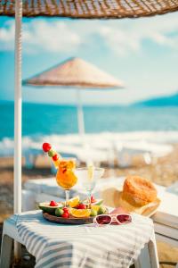 达特恰Feri Surf Club Hotel Datça的海滩上的一张桌子上放着一盘水果和一杯饮料