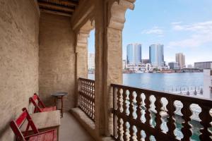 迪拜Al Seef Heritage Hotel Dubai, Curio Collection by Hilton的两把红色椅子坐在俯瞰着水面的阳台