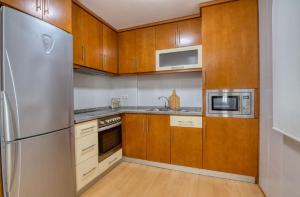 菲尼斯特雷O Aserradero的厨房配有木制橱柜和不锈钢冰箱。