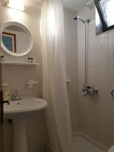 阿凯松Aktipis Studios的浴室配有盥洗盆和带镜子的淋浴