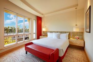 孟买ITC Maratha, a Luxury Collection Hotel, Mumbai的一间卧室设有一张大床和一张红色长凳
