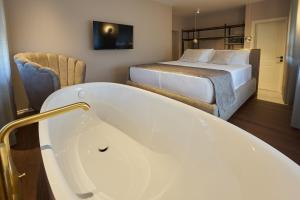 伊佐拉Dolcemente Garni Hotel Superior的一间位于床边的带浴缸的浴室