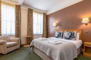 米尔顿凯恩斯天鹅复兴酒店的配有一张床和一把椅子的酒店客房
