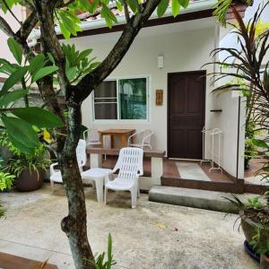 卡马拉海滩Bungalows Musch Kamala Phuket的庭院配有白色的椅子和桌子,设有门