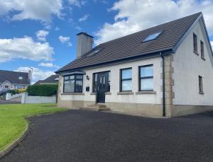 巴利卡斯尔Holiday Home in Ballycastle - Fáinne na Cairde的白色的房子,有黑色的门和窗户