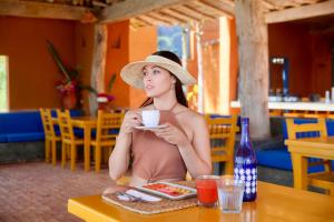 ParaguachiCala Margarita Hotel的坐在桌子边喝咖啡的戴帽子的女人